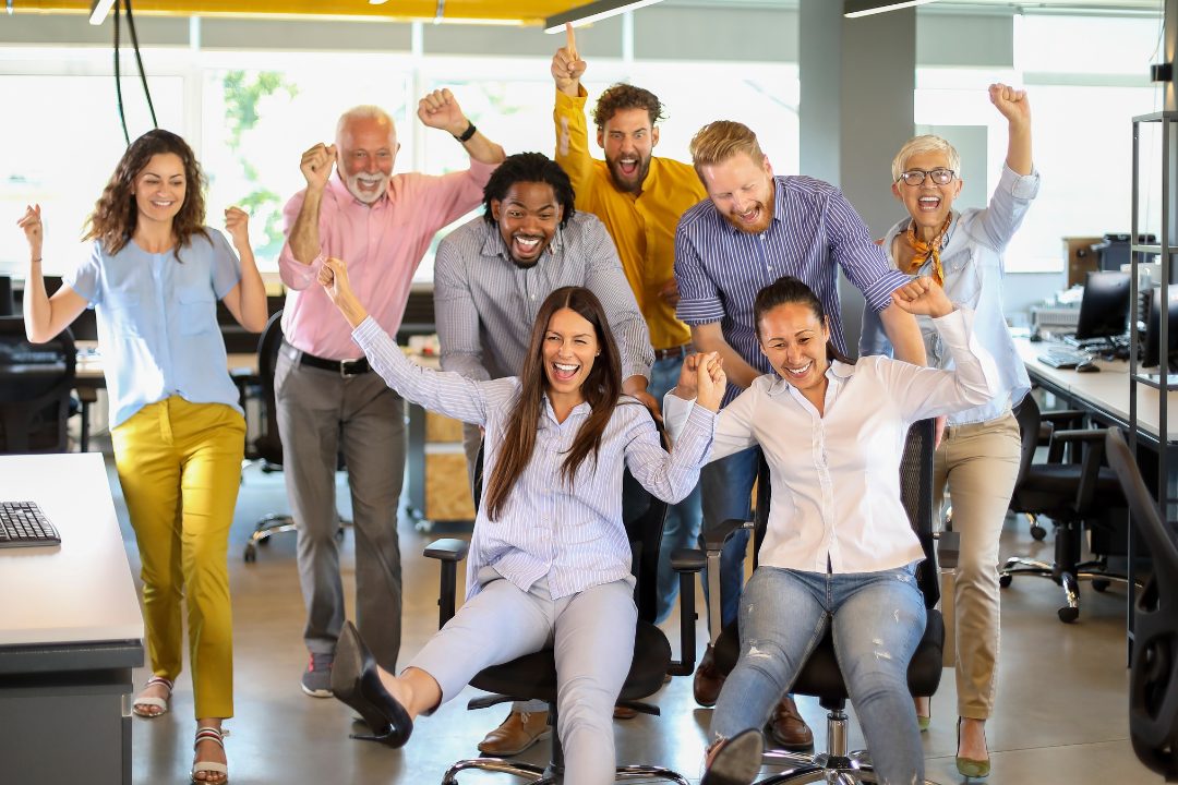 Team celebrating a successful moment in the office, symbolizing the positive impact of strong leadership and collaboration